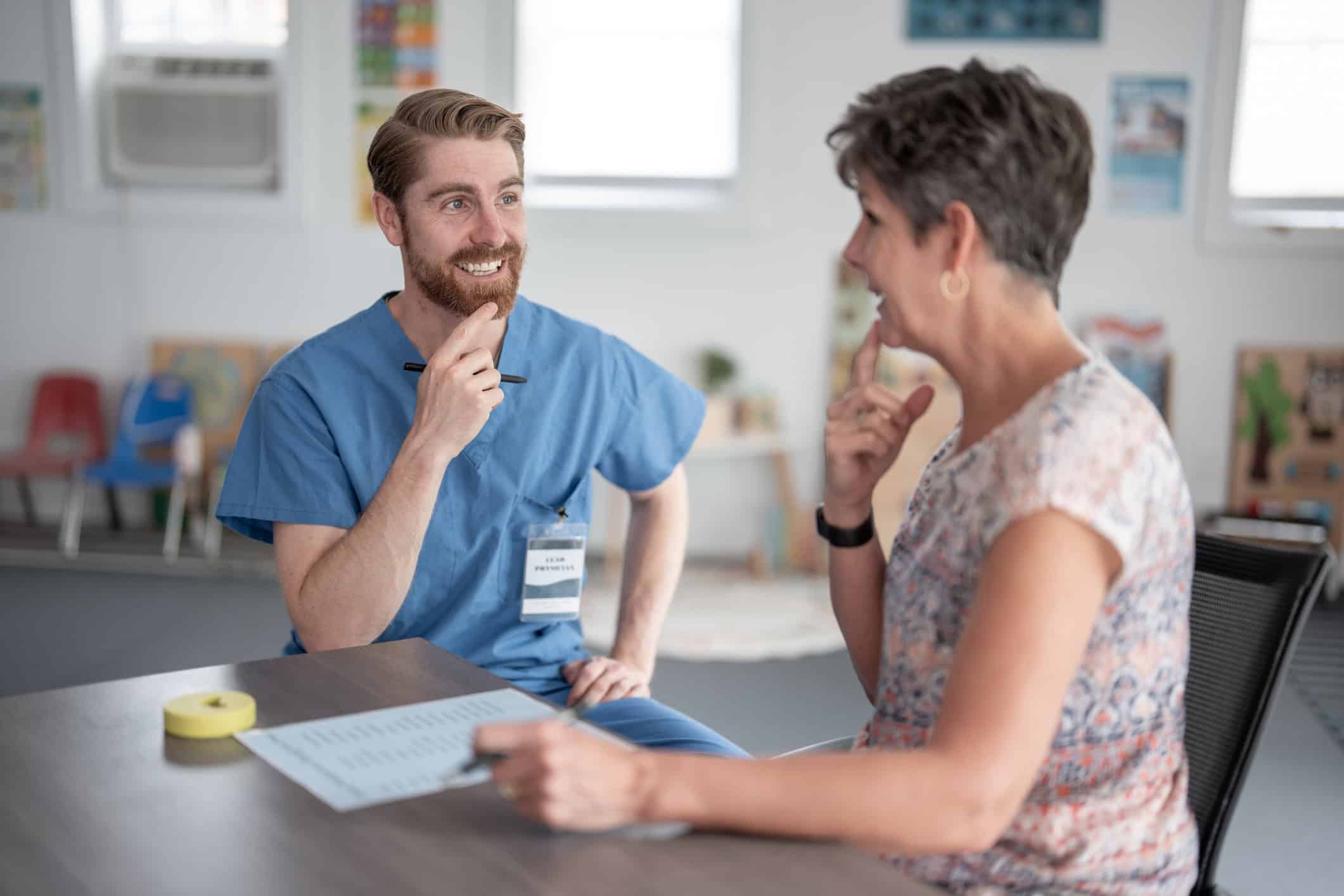 A professional therapist interacts with a patient during a speech therapy session, fostering communication and understanding. The setting suggests collaboration and expertise to aid in skill-building and self-expression.